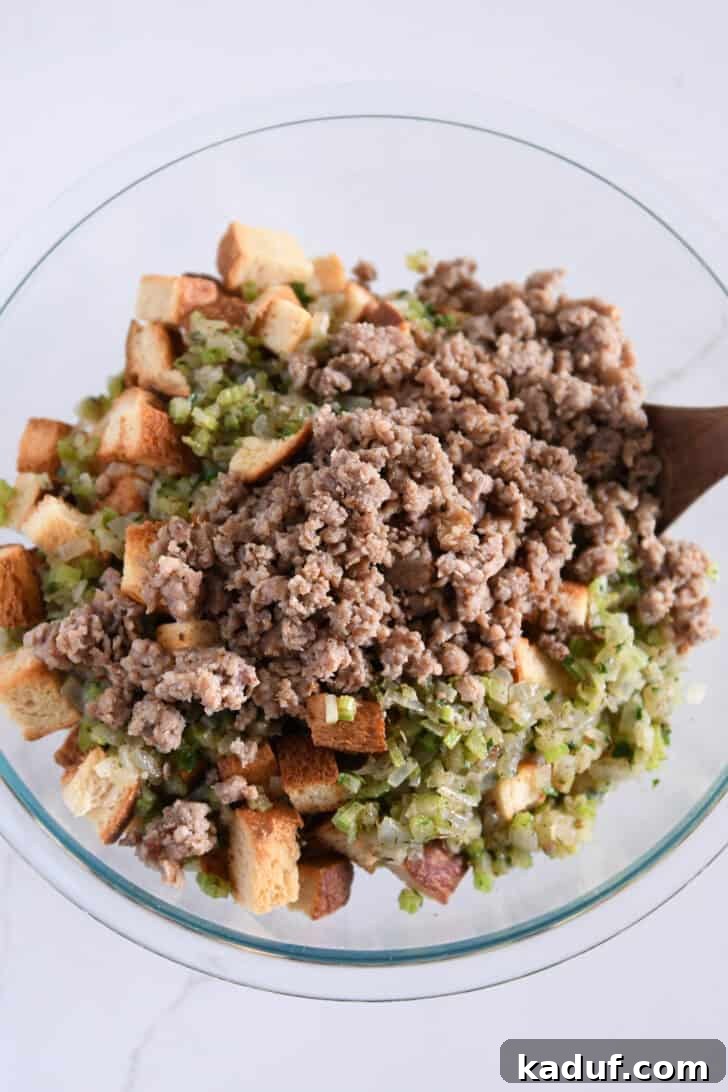 Hearty Sausage and Herb Stuffing 4 A large glass bowl containing toasted bread cubes, cooked vegetables, and crumbled sausage, pre-mixed for stuffing.