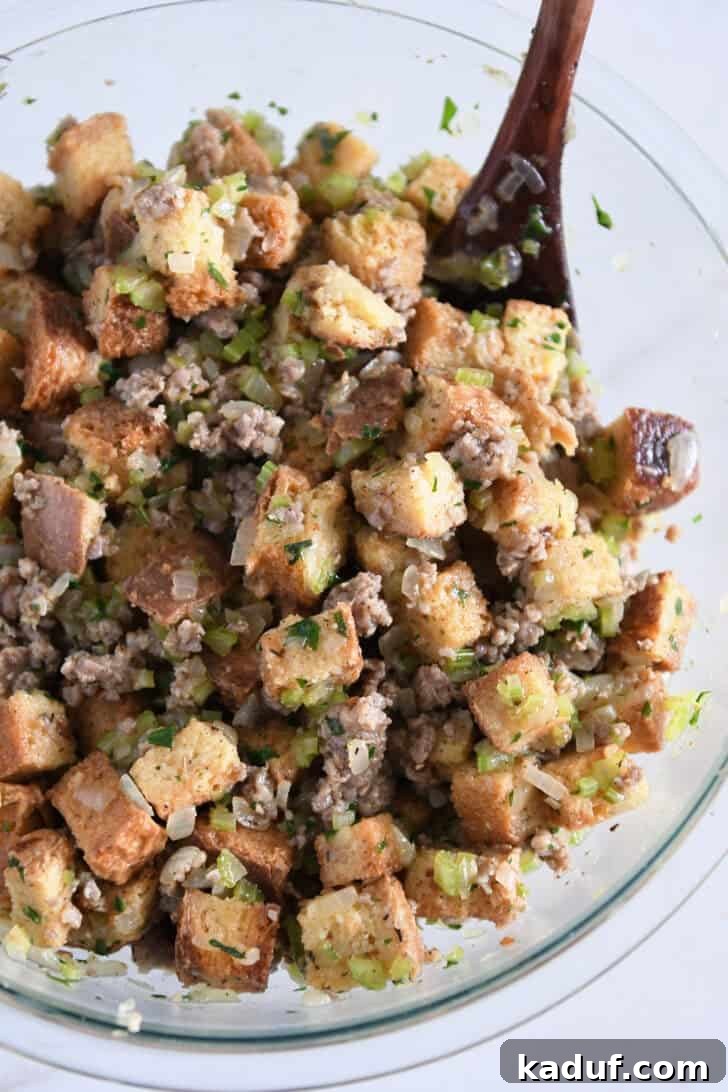 Hearty Sausage and Herb Stuffing 6 A glass bowl filled with a thoroughly mixed stuffing mixture, where bread cubes, sausage, vegetables, and broth are well-saturated.