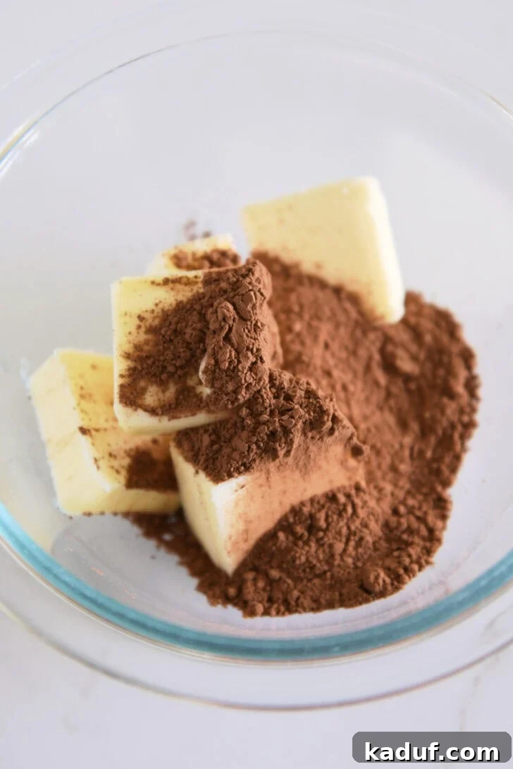 Velvet Chocolate Dream Pie 3 A clear glass bowl containing chunks of butter and a mound of natural, unsweetened cocoa powder, ready to be melted and combined for the pie filling.