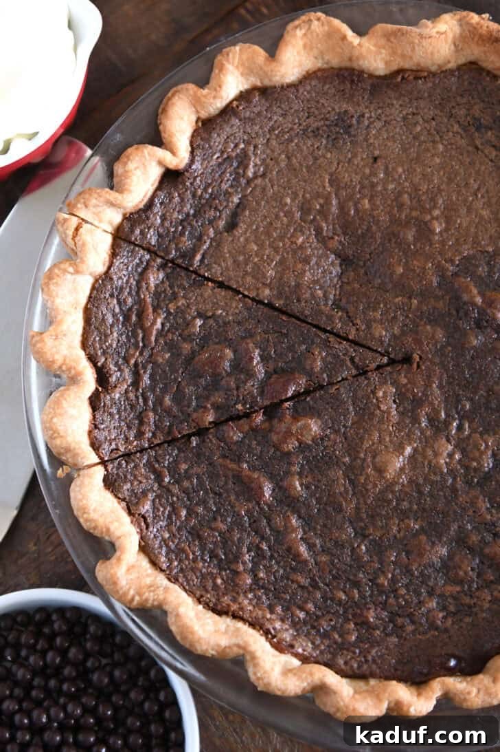 Velvet Chocolate Dream Pie 6 A top-down view of a freshly baked chocolate chess pie with a single slice partially cut, revealing the rich, dark fudgy filling beneath its signature crackly top.