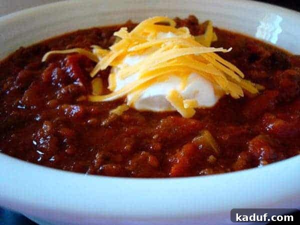 Sugarcane Spice Chili 10 White bowl with chili topped with sour cream and cheese.