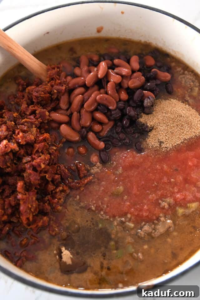 Sugarcane Spice Chili 5 Beef broth, crushed tomatoes, black beans, kidney beans, and sun-dried tomatoes in cast iron pot.