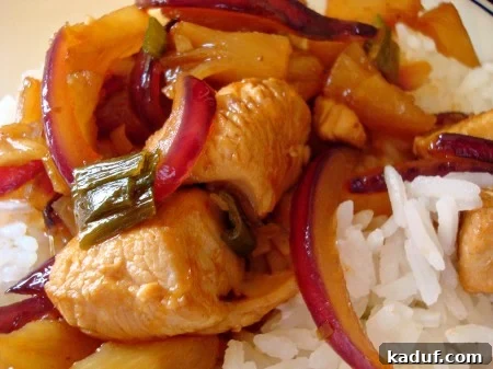Zesty Pineapple Chicken with Crisp Red Onion 2 Sweet and Sour Chicken with Pineapple and Red Onion served over white rice, garnished with fresh herbs.
