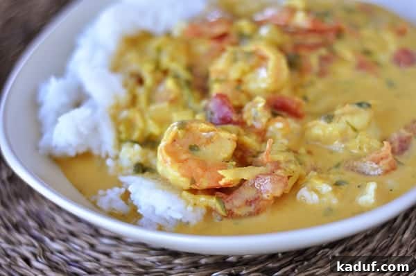 Creamy Coconut Shrimp Curry 13 White rice topped with a rich, creamy coconut shrimp curry mixture, garnished with fresh herbs.