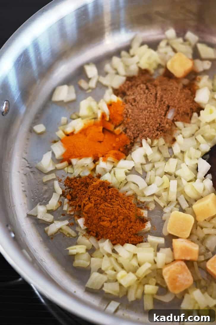 Creamy Coconut Shrimp Curry 4 Top down view of a metal pot with diced onions and curry spices sautéing.