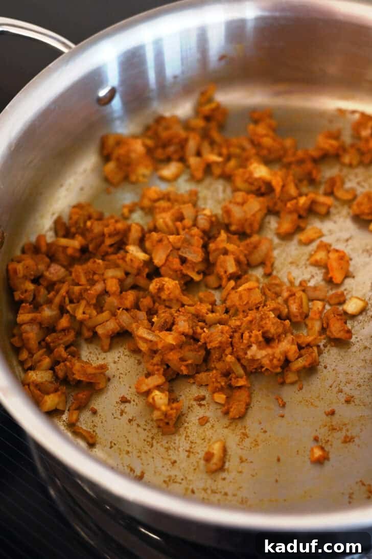 Creamy Coconut Shrimp Curry 6 Close-up of curry spices and onions simmering in a metal pot, creating a fragrant base.