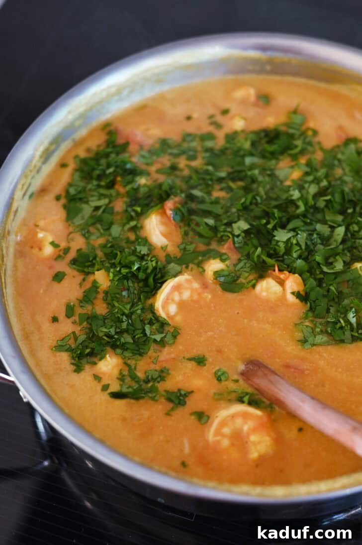 Creamy Coconut Shrimp Curry 8 Top down view of a finished shrimp curry in a metal pot, garnished with fresh chopped parsley or cilantro.