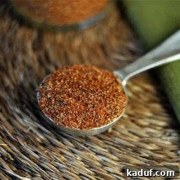 A small bowl of homemade taco seasoning with a spoon, ready to be used in cooking. The spices are vibrant and well-mixed.