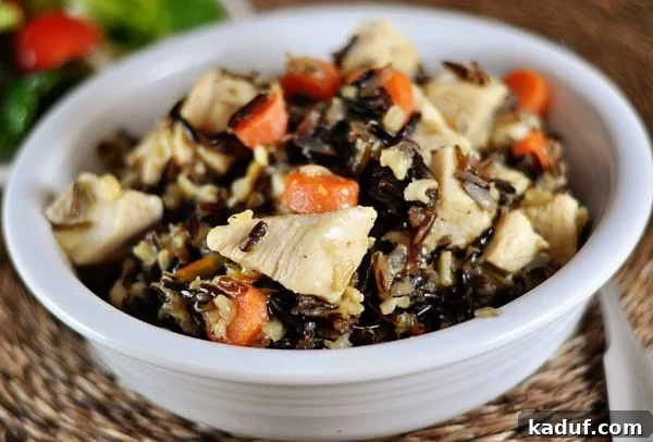 Aromatic Rosemary Chicken and Wild Rice 2 White bowl of cooked wild rice, carrot slices, and cubes of chicken seasoned with rosemary.