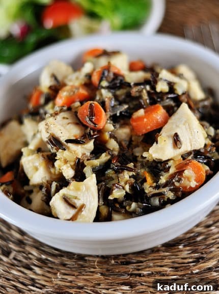 Aromatic Rosemary Chicken and Wild Rice 3 White bowl full of chicken cubes, cooked wild rice, and sliced carrots, ready to be served.