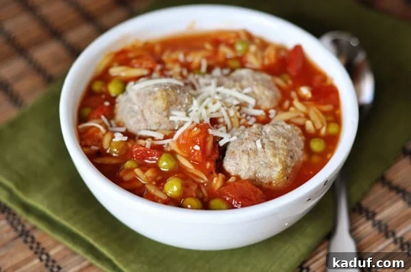 Hearty Meatball & Pasta Soup 2 A white bowl full of pea and orzo soup with three meatballs nestled in the middle.