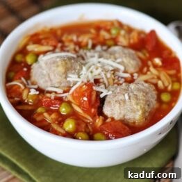 Hearty Meatball & Pasta Soup 4 A white bowl of pea and orzo soup with three meatballs nestled in the middle.