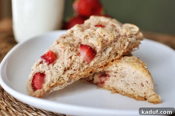Luscious Strawberry Cream Scones 2 Two strawberry-studded scones stacked on top of each other on a white plate, showcasing their inviting texture.