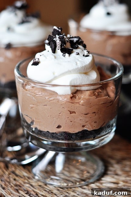 Decadent No-Bake Nutella Cheesecakes 2 Clear white goblet with no-bake nutella cheesecake with an Oreo crust, and topped with whipped cream and crushed Oreo.