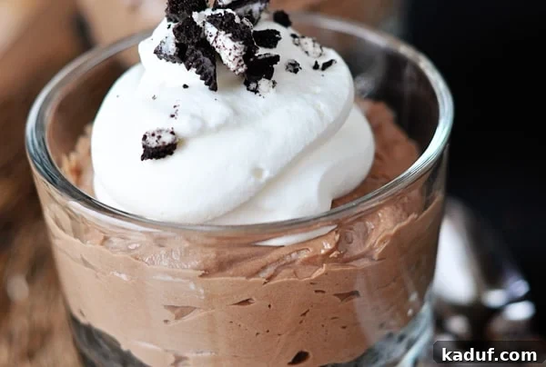 Decadent No-Bake Nutella Cheesecakes 3 Individual chocolate no-bake cheesecake in a glass goblet topped with whipped cream and crushed Oreo.