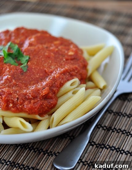 Blush Brie Pasta 2 Cooked tube pasta covered with vibrant red sauce, generously topped with fresh Parmesan, served on a pristine white plate.