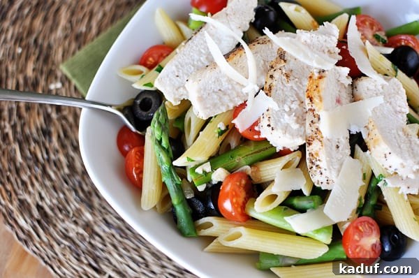 Fresh Spring Penne with Delicate Butter Sauce 2 White bowl with cooked penne pasta, asparagus, tomatoes, olives, and chicken strips.