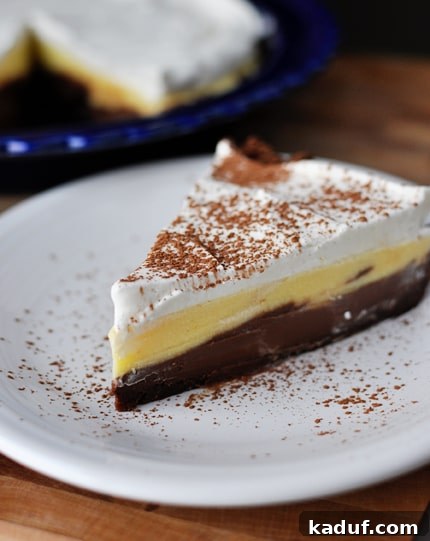 Decadent Dark Chocolate Cream Pie 4 A vertical shot of a Black Bottom Pudding Pie slice, showcasing the contrasting chocolate crust, creamy pudding layers, and light whipped cream topping, ready for enjoyment.