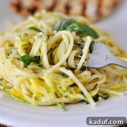 Garden Fresh Zucchini and Yellow Squash Noodles 4 A close-up shot of Zucchini & Yellow Squash Spaghetti on a white plate, garnished with fresh basil.