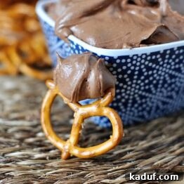 A small blue ceramic bowl with a spoonful of rich brownie batter dip, garnished with chocolate chips.