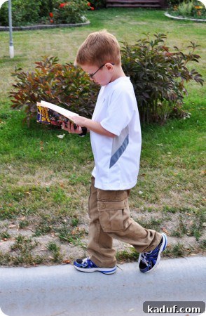 Walker's Reading Adventure and Tumble Walker, a young boy, intently reading a book while walking on a curb, just before a fall.