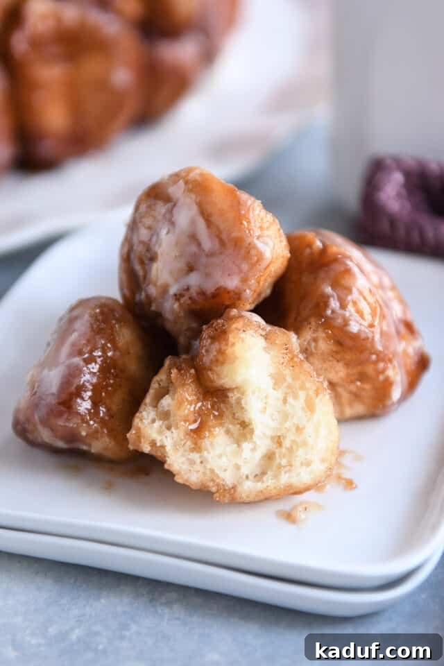 The Ultimate Sticky Pull Apart Monkey Bread 14 A small white plate holds four pieces of golden-brown monkey bread, one expertly cut in half to reveal its soft, tender interior.