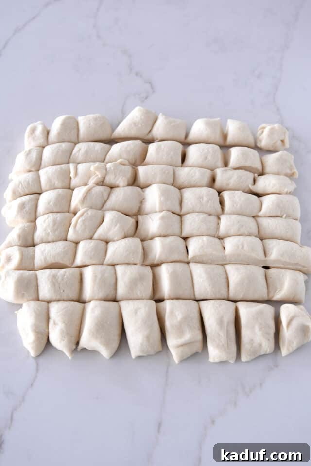 The Ultimate Sticky Pull Apart Monkey Bread 5 A sheet of dough meticulously cut into 64 small, even pieces on a countertop, prepared for individual shaping.