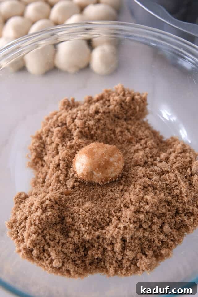 The Ultimate Sticky Pull Apart Monkey Bread 8 A butter-coated ball of dough being rolled in a bowl of cinnamon and brown sugar, acquiring its delicious outer layer.