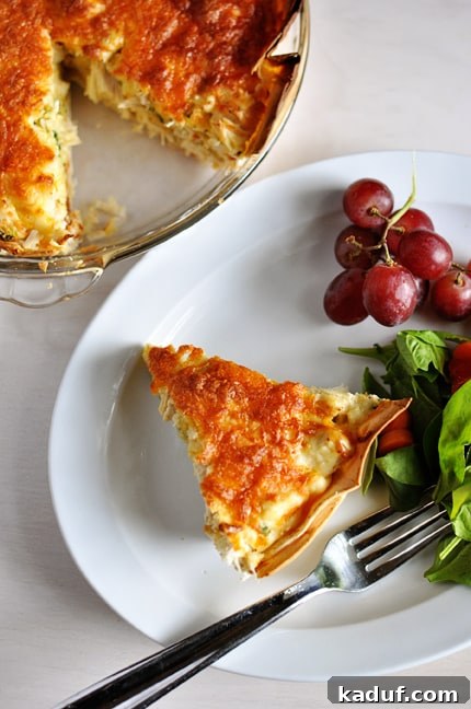 Deep Dish Cheesy Chicken Quesadilla 2 A slice of cheesy quesadilla pie on a white plate next to a cluster of grapes and green salad.