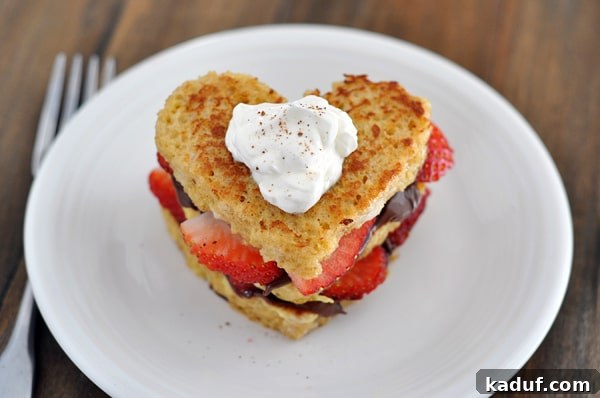 Strawberry and Nutella Bliss French Toast 2 Top view of a heart shaped chocolate and strawberry stuffed french toast on a white plate.