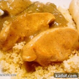 Close-up of a serving of chicken with green curry sauce on couscous.
