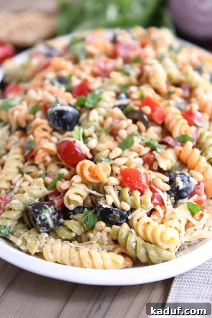 Vibrant Pasta Medley 2 A beautifully arranged tri-color pasta salad on a white oval platter, garnished with fresh basil leaves and parmesan cheese.