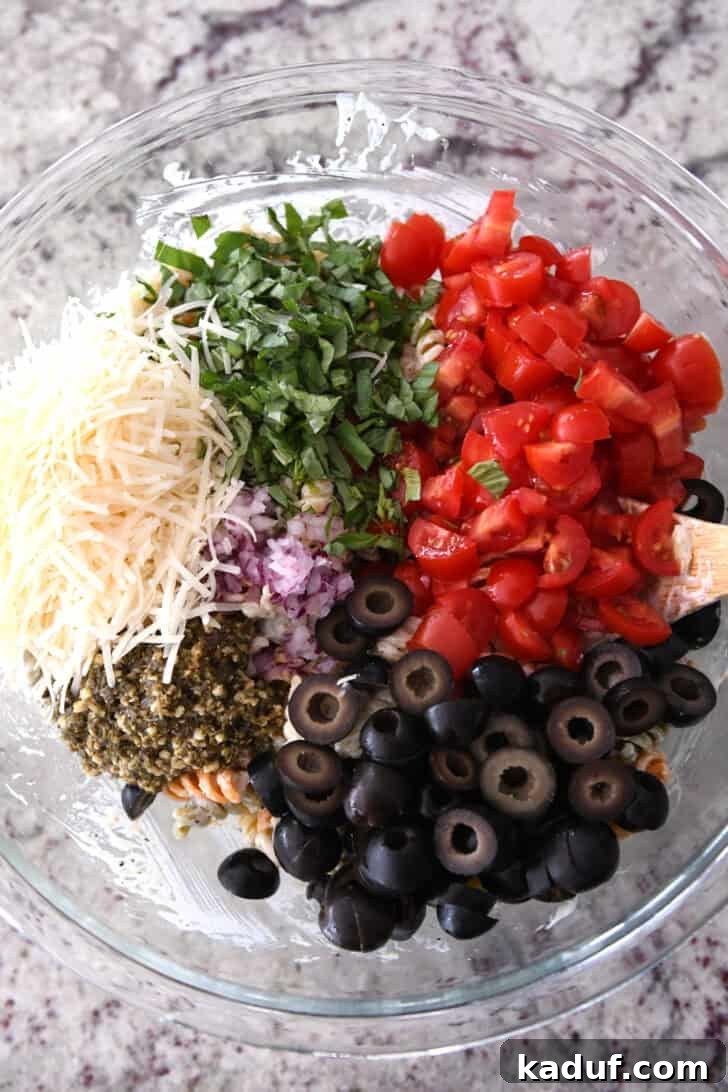 Vibrant Pasta Medley 5 A mix of diced olives, pesto, red onions, tomatoes, fresh basil, and parmesan cheese ready to be added to the pasta.