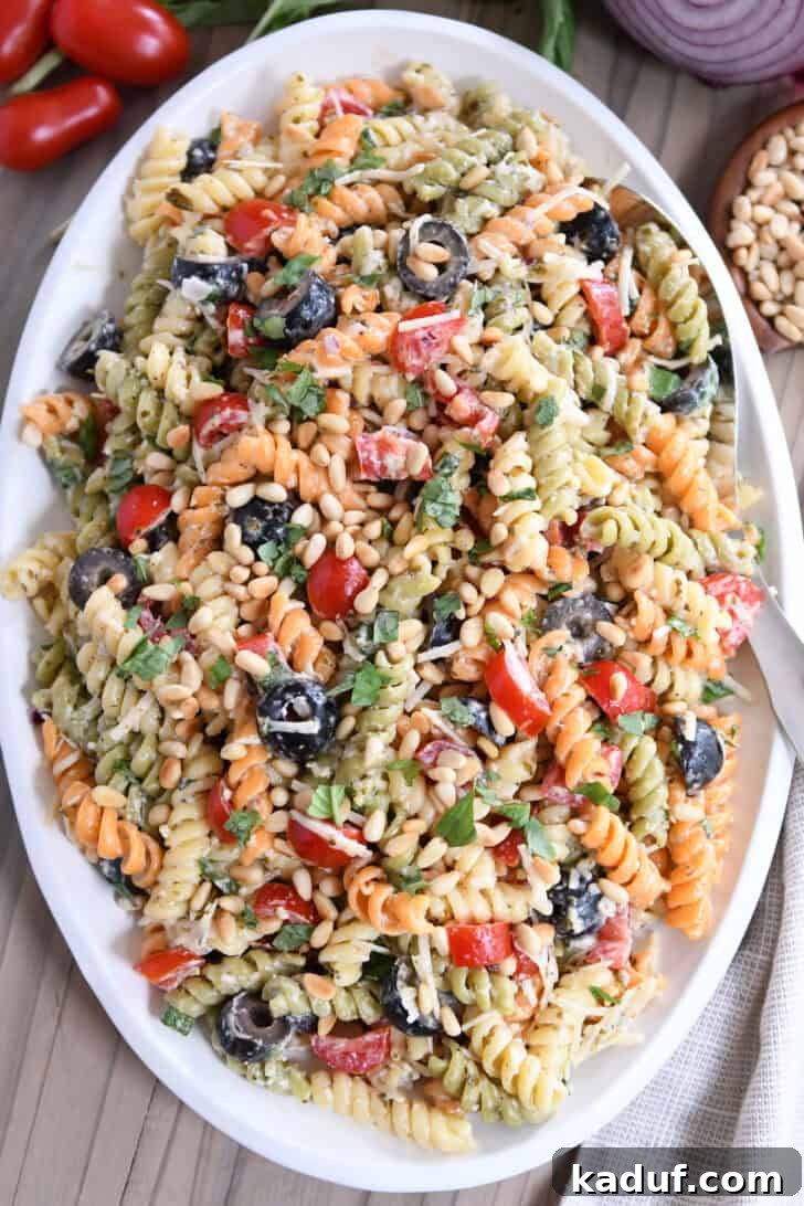 Vibrant Pasta Medley 8 Top-down view of a vibrant tri-color pasta salad overflowing on an oval white platter, ready for serving.