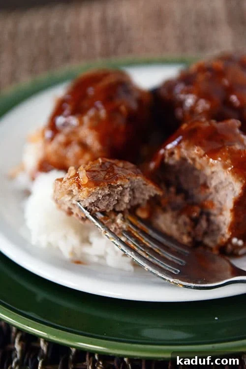 Tatlı Ekşili Köfteler 4 Sweet and sour meatballs over white rice with one meatball getting a bite taken out.