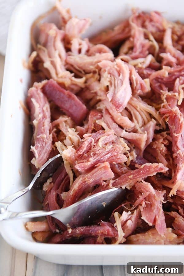 Sweet Glazed Baked Ham 2 Shredded sweet baked ham in white baking dish.