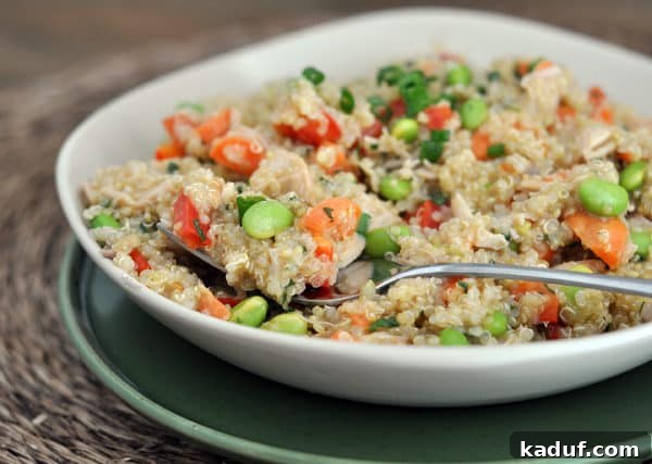Vibrant Thai Chicken Quinoa Salad 2 White bowl of cooked quinoa salad with edamame, peppers, and green onions.