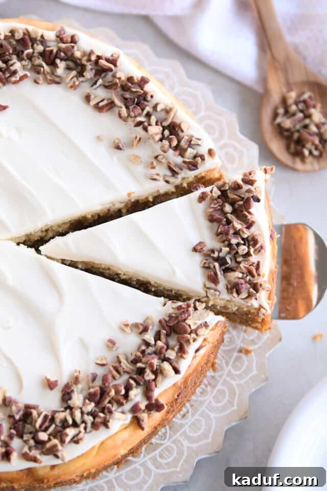 Carrot Cake Cheesecake Fusion 8 A perfectly triangular slice of carrot cake cheesecake, adorned with frosting, resting on a cake server, ready to be enjoyed.