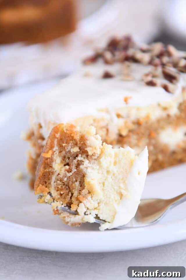 Carrot Cake Cheesecake Fusion 9 A close-up shot of a fork holding a bite-sized piece of carrot cake cheesecake, showing the fluffy frosting and cake layers.