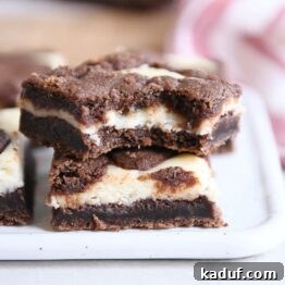 Zebra Cheesecake Brownies 11 A stack of black and white cheesecake brownies with a portion removed, showing the fudgy base and creamy top.