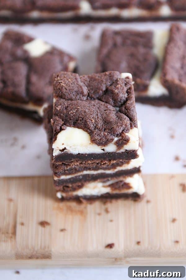 Zebra Cheesecake Brownies 9 Several black and white cheesecake brownies stacked on top of each other, highlighting their distinct layers.