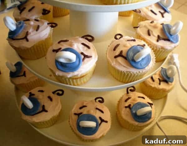 Sweet Baby Bites 2 Cupcakes decorated like tiny baby faces, complete with little swaddles, presented beautifully on a tiered cupcake stand, perfect for a baby shower.