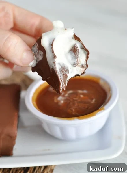 Decadent Polar Bars 2 A half-eaten chocolate ice cream bar melting over a bowl of rich caramel sauce, showcasing the decadent layers of brownie, ice cream, and chocolate shell.
