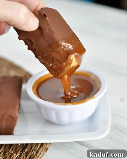Decadent Polar Bars 5 A chocolate-coated ice cream bar, freshly dipped in a bowl of glistening caramel sauce, ready to be enjoyed.