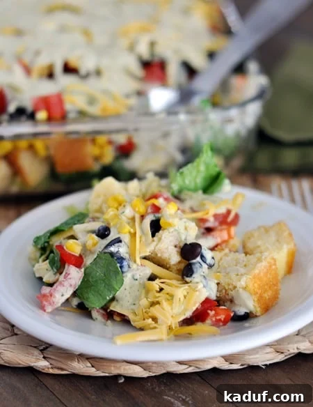 Stacked Mexican Cornbread Salad 3 A serving of Mexican cornbread salad on a white plate, showing the distinct layers and vibrant colors.