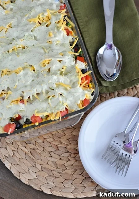 Stacked Mexican Cornbread Salad 4 Top-down view of a 9x13 inch glass dish filled with the colorful layers of Mexican cornbread salad, topped with cheese and dressing.
