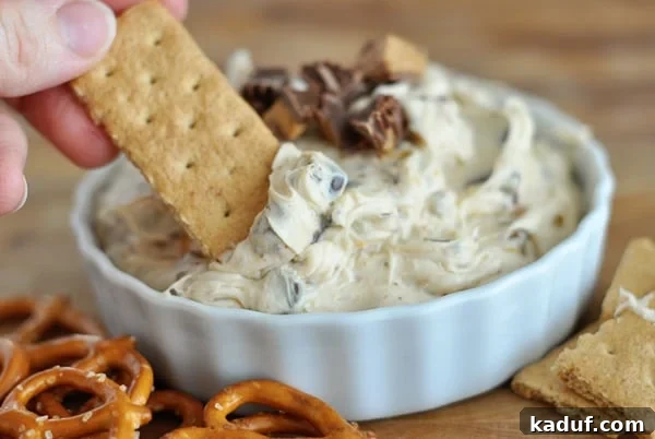 Decadent Peanut Butter Cookie Dough Dip 2 A white bowl full of peanut butter cookie dough dip with a graham cracker dipped in it.
