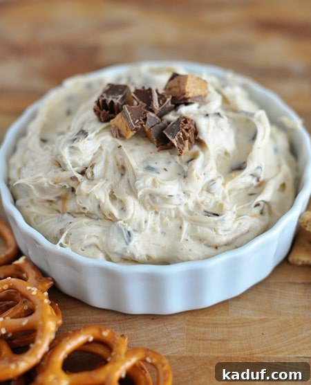 Decadent Peanut Butter Cookie Dough Dip 3 Top view of a white bowl full of peanut butter dip with chopped peanut butter cups on top.