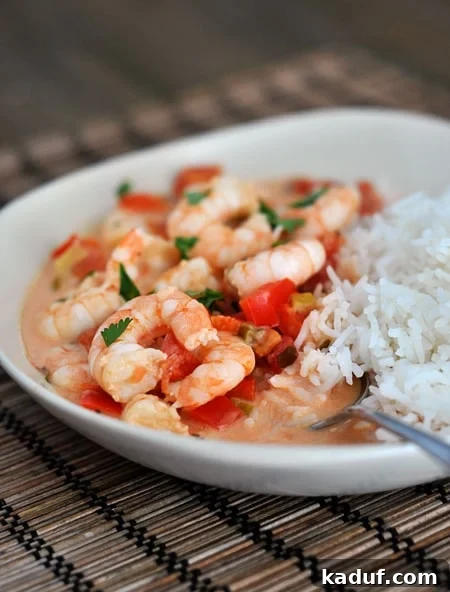 Garlic Shrimp Skillet with Coconut Lime Tomato Sauce 3 A white bowl with cooked shrimp in a garlic lime tomato sauce and cooked white rice.