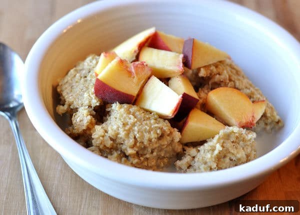 Golden Oat Bake 3 A white bowl of baked oatmeal with fresh peach slices arranged on top.